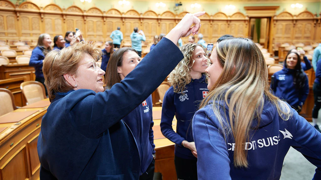 Die Sportsministerin erklärt den Spielerinnen das Wandbild im Nationalratssaal und informiert über die Abläufe im Ständeratssaal.