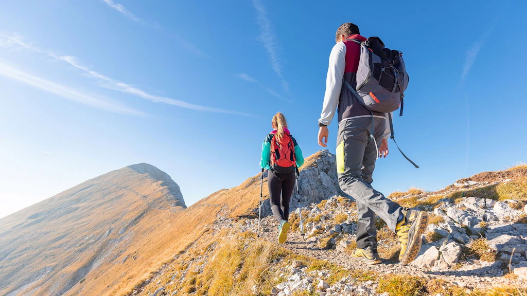 Zwei Personen wandern in den Bergen einem Grat entlang