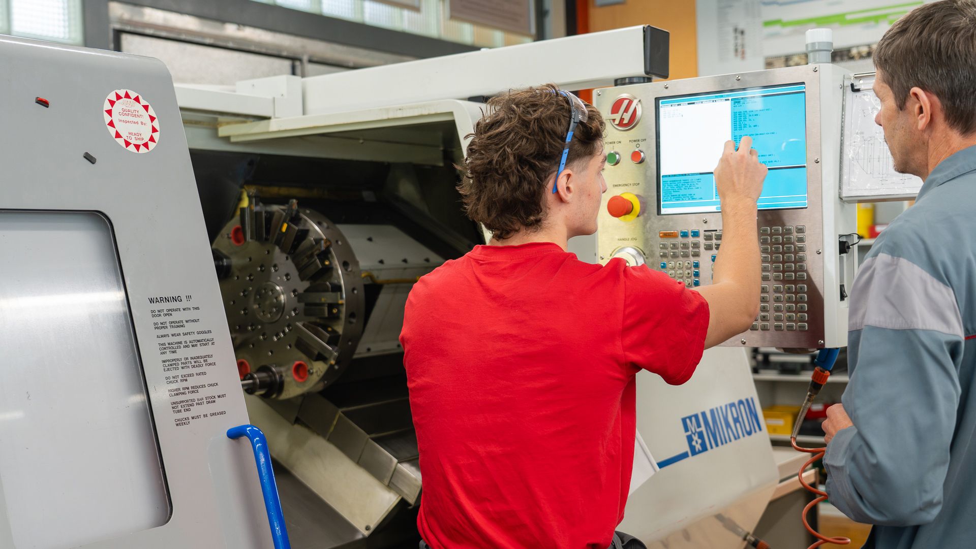 Francis Emery im Gespräch mit einem Lernenden über eine Maschine der Lehrwerkstatt 