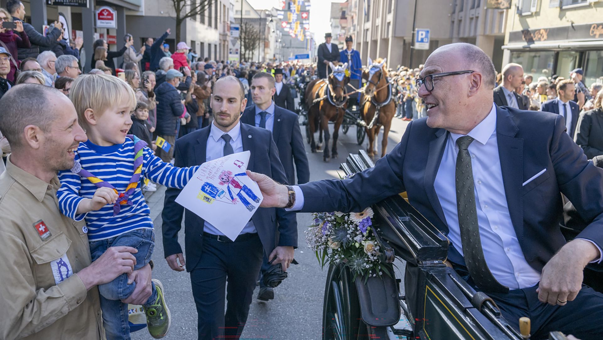 Martin Pfister nimmt von einem Kind eine Zeichnung entgegen.