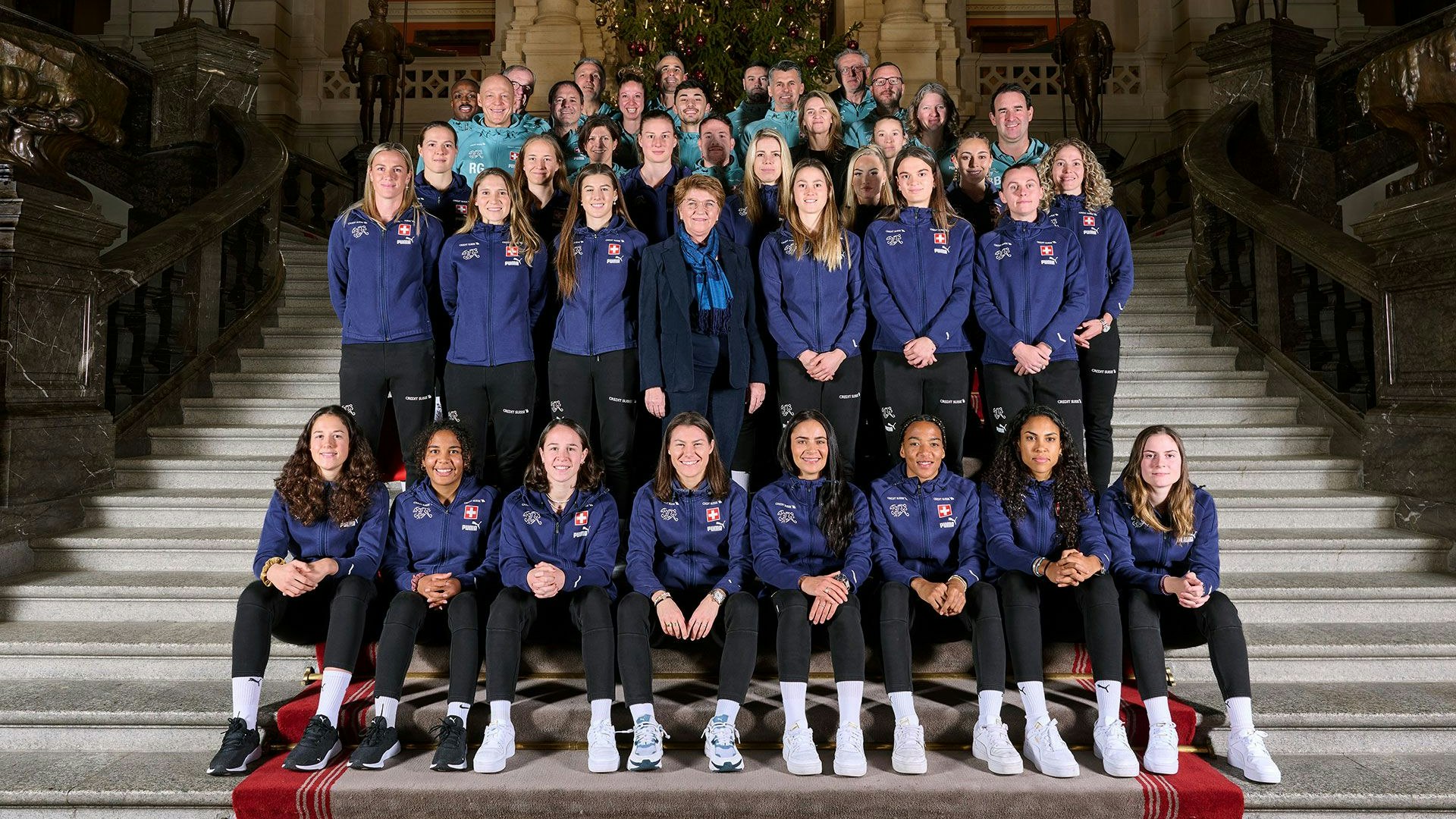 La conseillère fédérale entourée des joueuses et de l’équipe d’encadrement de l’ASF dans le grand hall du Palais du Parlement.