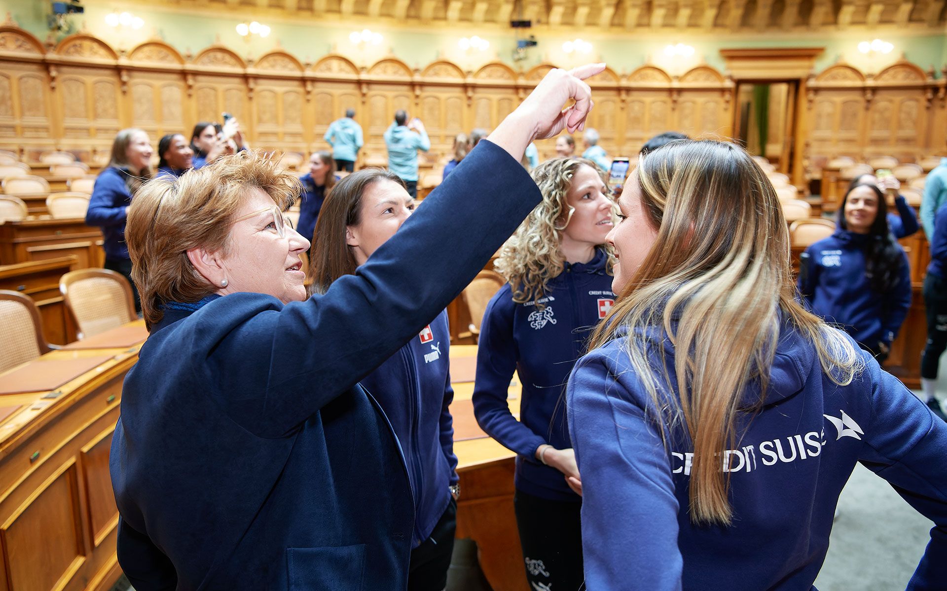 La ministra dello sport spiega alle giocatrici il dipinto murale nella sala del Consiglio Nazionale e le informa sulle procedure nella sala del Consiglio degli Stati.