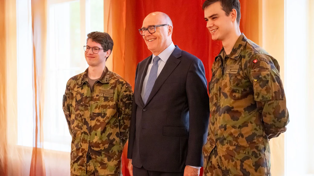 Il consigliere federale Martin Pfister si mette in posa durante la colazione con i parlamentari con i due militari che hanno assolto la SR Spazio cosmico Jonas Troeltsch e Cyrill Marti.